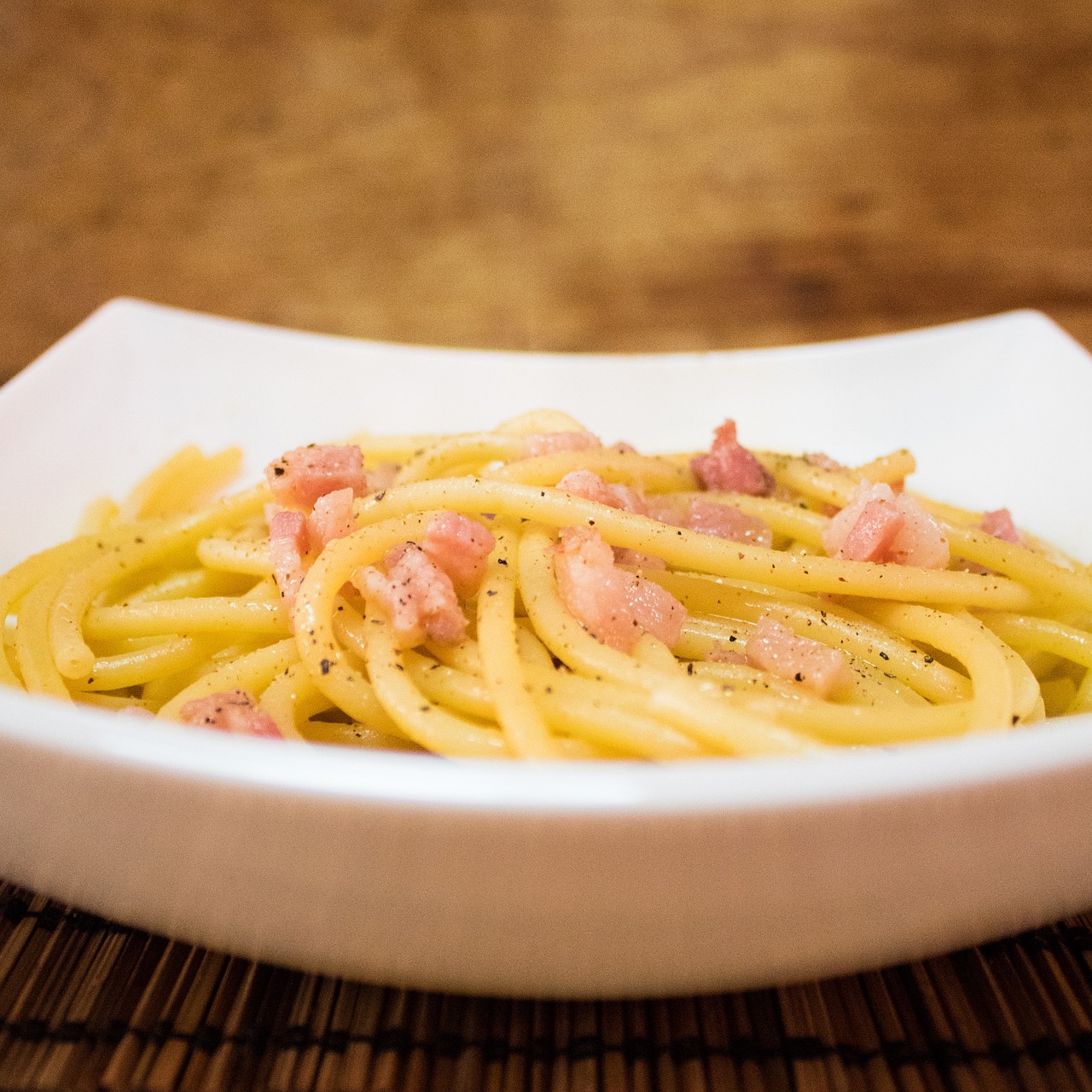 Pasta alla carbonara servita in un piatto, con guanciale croccante e spolverata di pecorino.