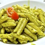Pasta al pesto servita in un piatto tipico ligure, con basilico fresco e pinoli.