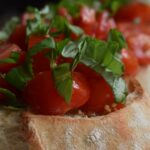 Bruschette al pomodoro su un tagliere, pronte per essere gustate, con ingredienti freschi e colorati.